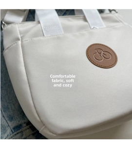Gros plan du tissu du sac fourre-tout en toile crème avec logo en cuir sur fond de denim
