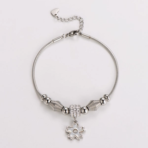 Macro view of silver snake chain bracelet featuring a sparkling white flower pendant