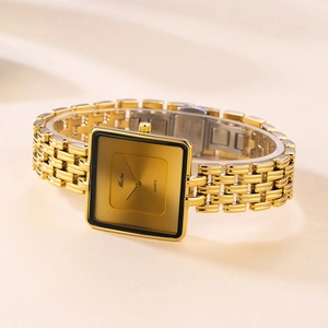 Close-up of golden square quartz watch with metal link strap on soft fabric