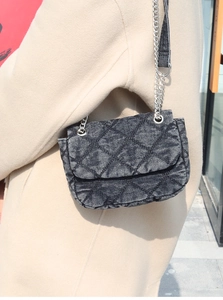 Close-up of gray denim quilted shoulder bag featuring silver metal chain and rhombus pattern