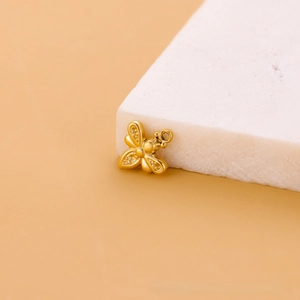 Détail d'un pendentif abeille dorée aux ailes texturées sur un support en marbre
