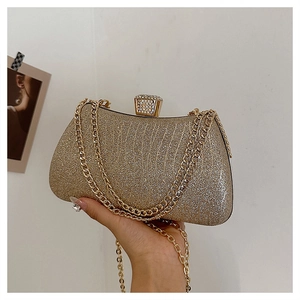 Detail of gold glitter evening clutch bag with sparkling diamond clasp and chain strap