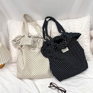 Polka dot canvas tote bag detail featuring ruffled lace edges and brand label studio patch