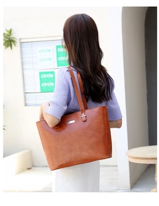 Brown large tote bag with textured leather and long shoulder strap worn by a model