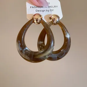 Detailed view of teardrop resin earrings with brown marble texture and gold metal
