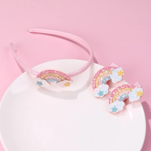 Detail of pink glitter rainbow headband and star clips for children on a white plate
