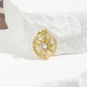 Macro detail of golden sunburst pendant with zircon and shell inlay on a white stone