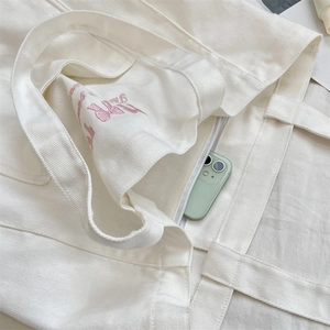Vue macro du sac en toile avec broderie rose et smartphone dans la poche intérieure