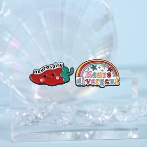 Red chili and rainbow enamel pins with Neurospicy and Neurodivergent text on light blue base