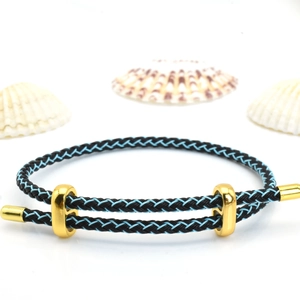 Close-up of black and blue braided steel wire bracelet with golden metal slider buckle