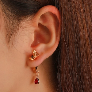 Close-up of gothic sword earring with red teardrop gemstone on a gold-plated hook