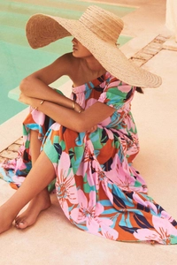 Abito a fiori monospalla con un grande cappello di paglia a bordo della piscina