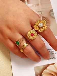 Retro gold rings set with pearl, emerald, and ruby stones on an open book background