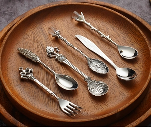 Detail of vintage silver coffee spoon set with royal crown and floral handles on tray