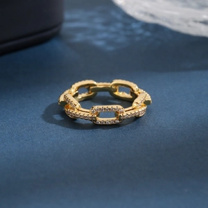 Minimalist gold chain link ring with pavé zircon stones on a dark textured background