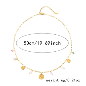 Détail d'un collier doré avec perles irrégulières et pendentifs métalliques martelés
