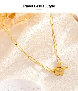 Detailed close-up of golden paperclip chain necklace with decorative floral toggle clasp
