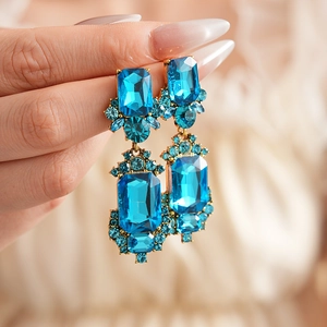 Close-up of vintage gold earrings featuring large blue rectangular gemstones