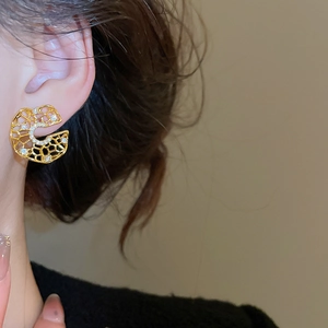 Close-up of elegant gold hollow honeycomb earrings with zircon stones on a female model