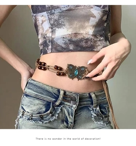 Detail of bohemian waist chain with bronze butterfly buckle and blue gemstone inlay