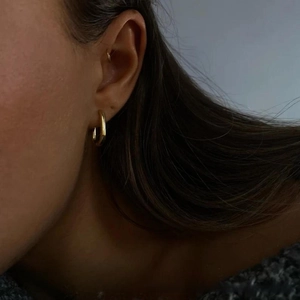 Primo piano di un orecchino a cerchio minimalista in acciaio inox placcato oro 18k