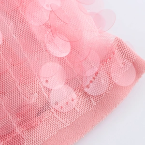 Détail macro de paillettes roses cousues sur un tissu en maille pour robes de soirée