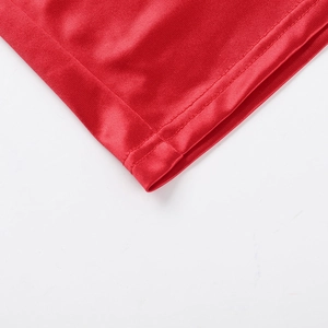 Detailed macro shot of double-stitched hem on the elegant red satin dress fabric