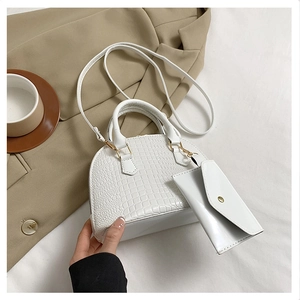 Detailed macro view of white crocodile pattern shell bag with matching envelope pouch