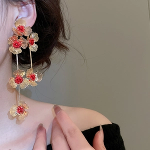 Detail of vintage hollow flower earrings with long tassels and red beaded center