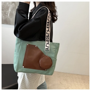 Detail of large green canvas tote bag with brown leather pocket and geometric strap