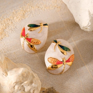 Macro detail of oval gold-plated earrings featuring enamel dragonfly with colorful wings