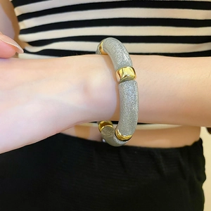 Detailed shot of an iridescent acrylic geometric bracelet featuring grey glitter tube beads