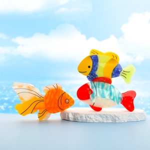Detail of colorful acetate tropical fish hair claws on a beach-themed background