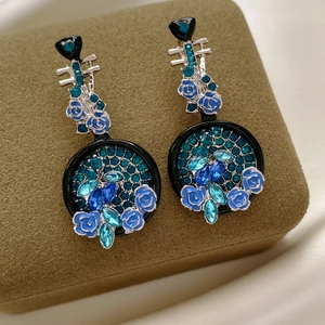 Dettaglio di orecchini vintage con rose in smalto blu e cristalli incastonati