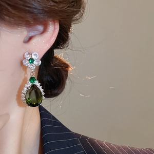 Dettaglio di eleganti orecchini a fiore con pendenti a goccia in zircone verde su modella