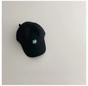 Détail d'une casquette enfant en coton noir avec broderie florale jaune et verte sur le devant