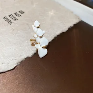Elegant gold-plated white orchid ear clip earring on a textured aesthetic card