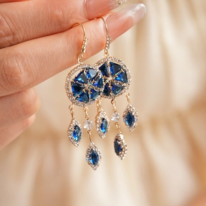 Detail of vintage gold earrings with blue faceted gems and white zircon tassels
