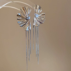 Close-up of silver tassel earrings with zircon flower design on a transparent stand