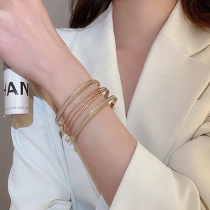 Detail view of layered gold-tone bracelets featuring matte finish and fine chain design