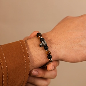 Detailed shot of men's wolf head bracelet featuring tiger eye beads on a male wrist