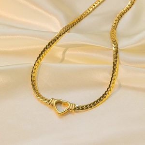 Detail of a golden heart-shaped clasp on a snake chain over beige silk background
