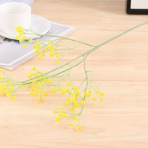 Detailed close-up of yellow artificial baby's breath flowers on light wood surface