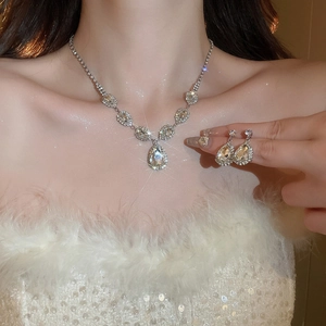 Close-up of model wearing silver teardrop rhinestone necklace and earring set