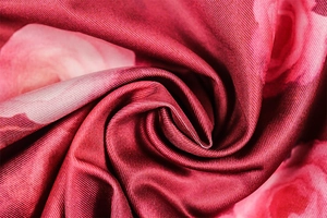 Macro del tessuto di raso con stampa floreale rossa che mostra texture e drappeggio