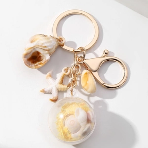 Detail van strandthema sleutelhanger met zeester, schelpen en miniatuur zandbol-hanger