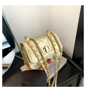 Macro detail of golden quilted small crossbody bag with metallic chain and turn-lock