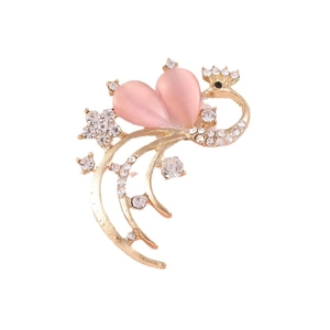 Golden peacock brooch with pink cat eye stones and white rhinestones on white background