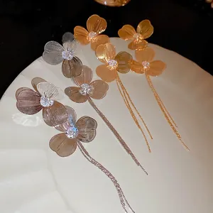 Boucles d'oreilles fleuries dorées avec glands et cristaux sur assiette décorative