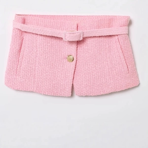 Pink tweed shorts with matching belt and gold decorative button in a flat lay view